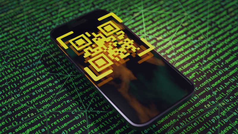 Ein Smartphone mit einem gelben QR-Code auf dem Bildschirm vor einem grünen Hintergrund mit binären Codemustern. Das Bild suggeriert die Themen Technologie und Sicherheit und bezieht sich auf die Botschaft 'QR-Phishing ist auf dem Vormarsch'.'