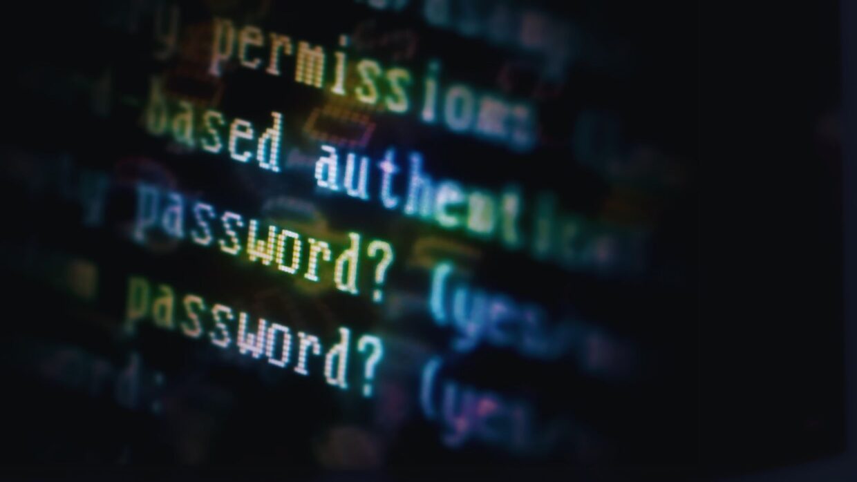 Nahaufnahme eines Computerbildschirms mit Codezeilen zur Authentifizierung, einschließlich des Wortes 'password?', das auf die erforderliche Benutzereingabe hinweist. Das Bild bezieht sich auf Themen wie Adversary-in-the-middle-Angriffe.