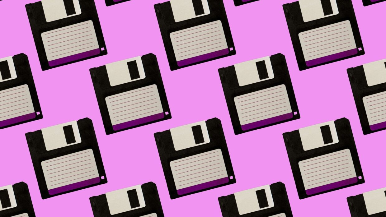 Ein Muster aus schwarzen und weißen Disketten auf rosa Hintergrund, das Retro-Technologie und Datenspeicherung illustriert und für die Geschichte der Ransomware relevant ist.
