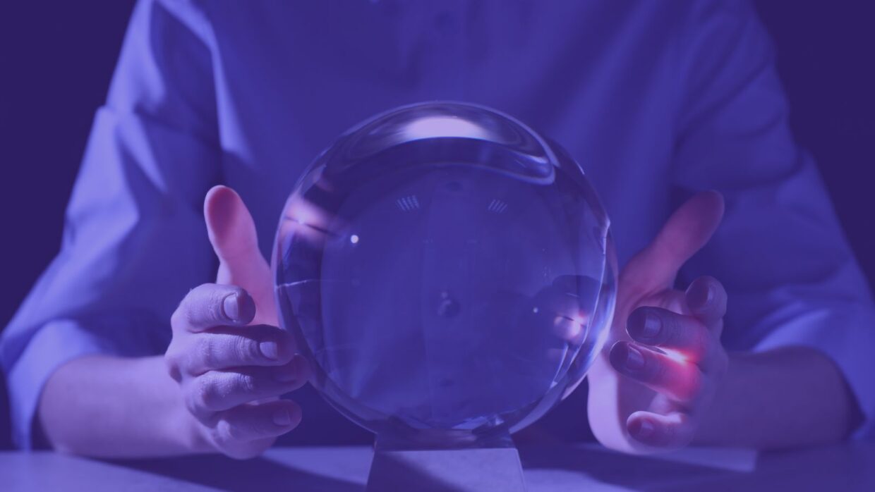 Eine Person, die mit beiden Händen eine Kristallkugel vor einem violetten Hintergrund hält. Die Kugel ist klar und reflektiert das Licht, was auf Mystik oder Vorhersage hindeutet.